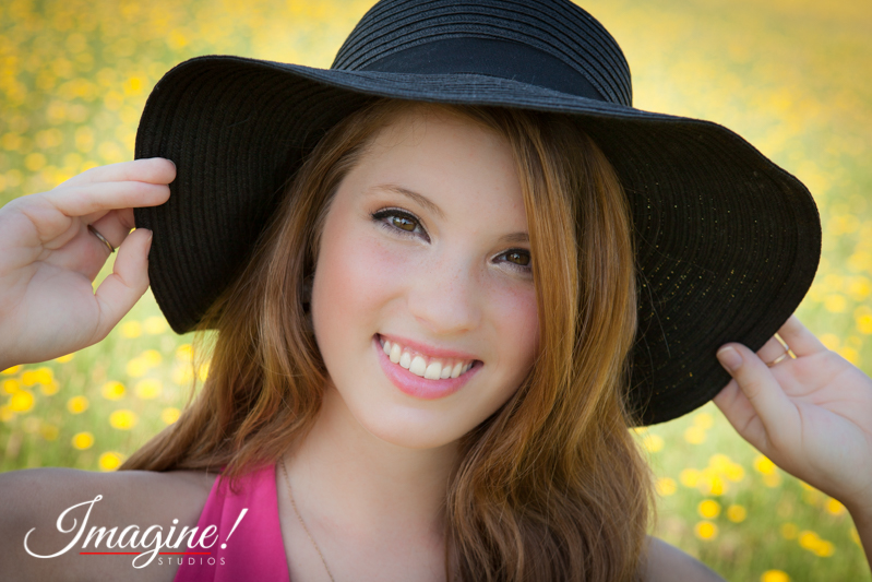 Bethany smiles in her sun hat during her senior model outdoor photo session in a wildflower field in Greer, SC