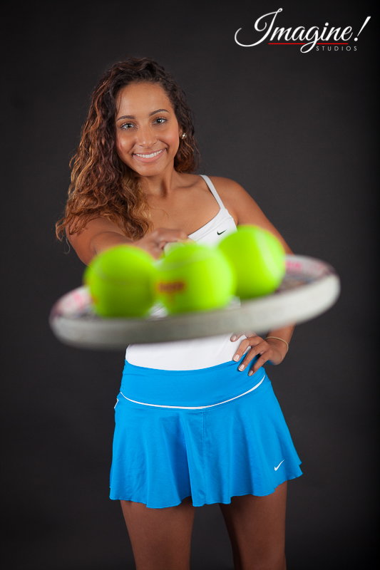 The camera focuses on Brianna as she stretches out her tennis racquet toward the photographer