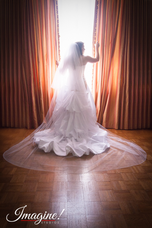 Layne stands at the window and displays the back of her wedding dress