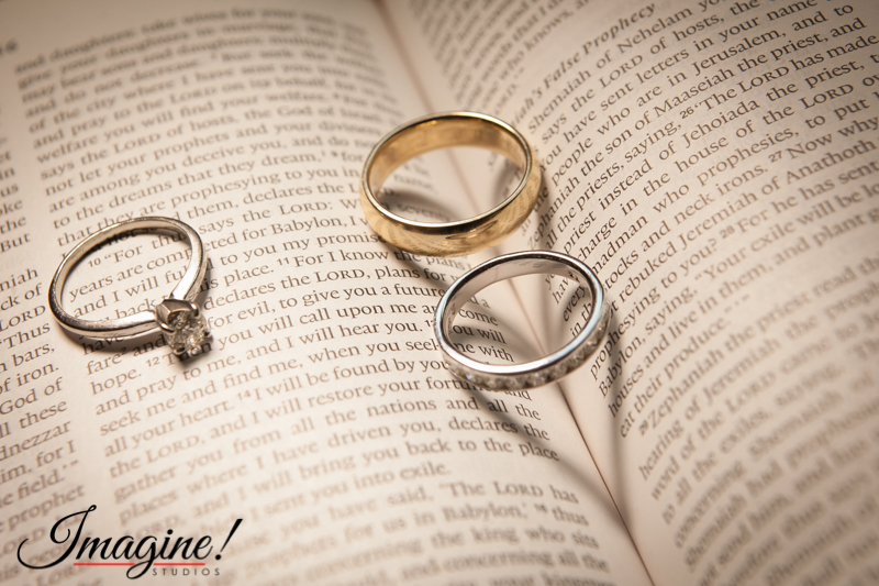 Wedding rings rest on the Bible creating shadow hearts under the light