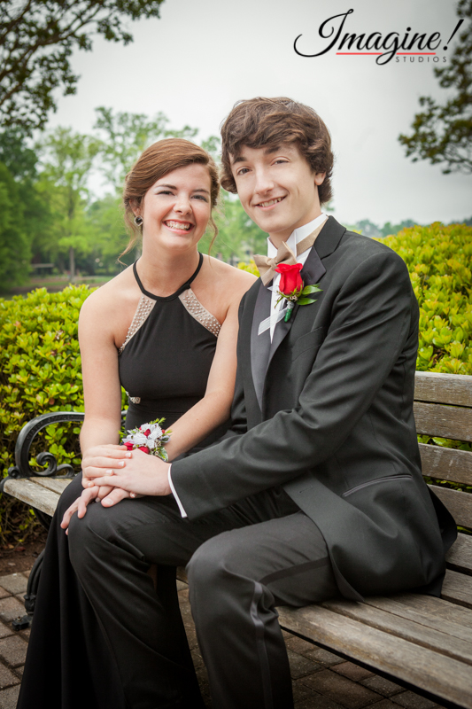 Jacob and Savannah hold hands while sitting on a bench by the Furman bell tower and lake